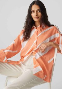 Camicia a righe arancione e bianca realizzata in tessuto leggero, con maniche lunghe, apertura con bottoni e vestibilità comoda.