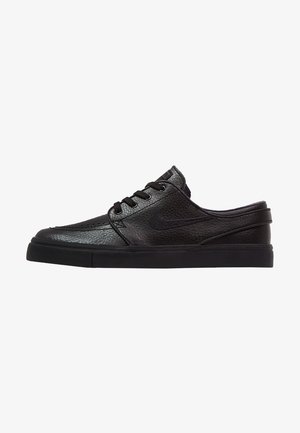 Baskets noires en cuir à enfiler avec lacets, tige texturée, semelle plate et logo Nike swoosh subtil sur le côté, vues de l'extérieur.