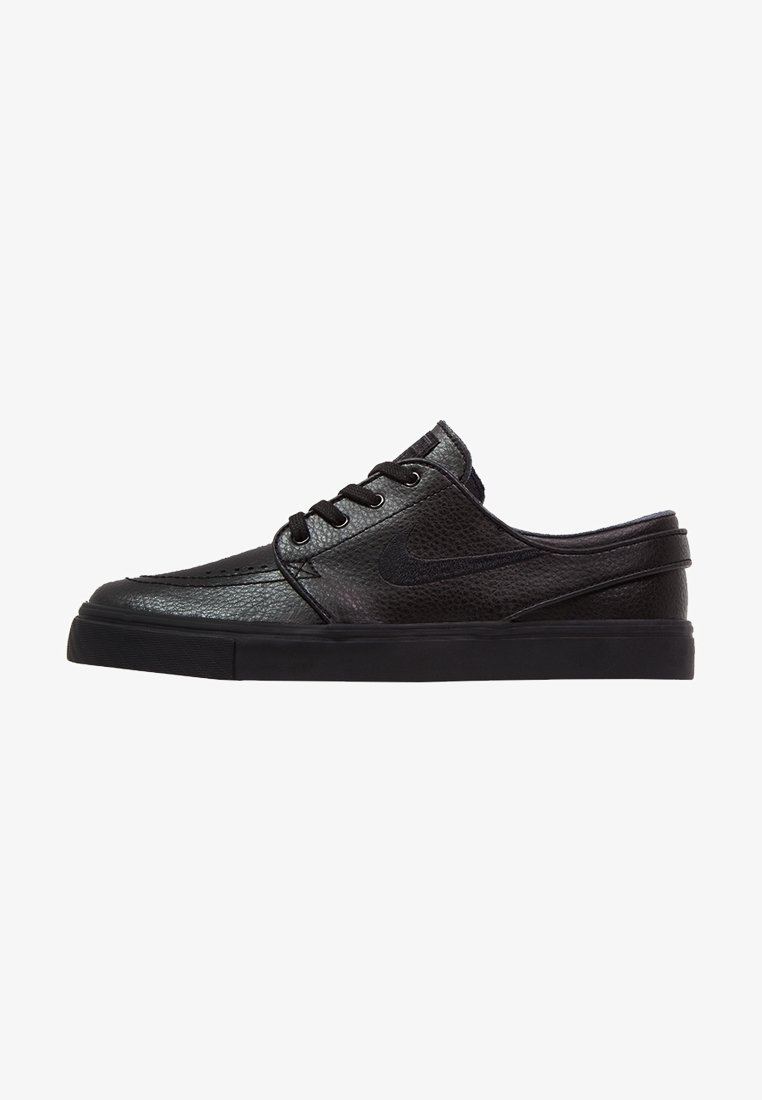 Baskets noires en cuir à enfiler avec lacets, tige texturée, semelle plate et logo Nike swoosh subtil sur le côté, vues de l'extérieur.