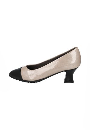 Zapato de salón de charol beige con punta negra, diseño redondeado y un pequeño tacón acampanado. Acabado texturizado con acentos suaves.