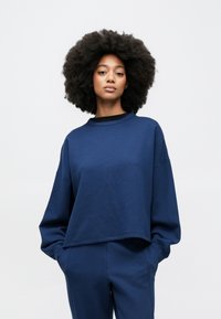 Μπλε ναυτικό κοντό φούτερ με άνετη εφαρμογή, στρογγυλή λαιμόκοψη και μακριά μανίκια. Απαλή υφή με λείο ύφασμα. Συνδυασμένο με κάτω μέρος που ταιριάζει.