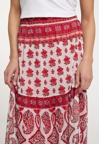 Maxirock mit rotem Blumenmuster, ausgestattet mit einem gerafften Taillenbund, mehrlagigem Design mit unterschiedlichen Blumenelementen und leichtem Stoff.