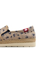 Zapato slip-on beige con patrones en azul marino, plantilla intermedia de estilo yute tejido, suela de goma y un parche de logo rojo en el talón.