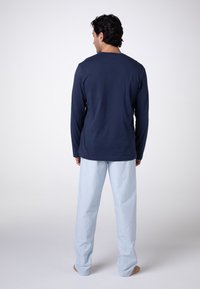 Camicia a maniche lunghe blu marina abbinata a pantaloni da pigiama a righe blu chiaro, con una vestibilità rilassata e tessuto morbido, vista dal retro.