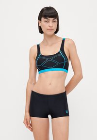Brassière de sport noire avec des accents géométriques turquoise, bretelles ajustables, associée à un short de sport noir avec un petit logo turquoise.