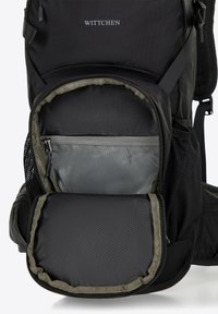 La mochila negra cuenta con un exterior texturizado, compartimentos con cremallera y un bolsillo interior forrado en gris. El logo "WITTCHEN" se muestra de manera prominente.