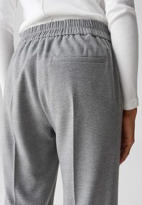 Grijze geruiten broeken met een elastische tailleband, voorzien van een enkele achterzak en een zachte, gestructureerde stof.