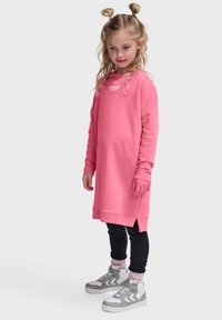 Rosa sweatshirtklänning med långa ärmar, ribbade ärmslut och sidslitsar. Matchad med svarta leggings och grå högklackade sneakers med vita detaljer.
