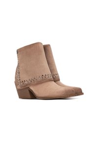 Botines de ante en color arena con punta afilada, que presentan un diseño de tachuelas a lo largo de la parte superior y un tacón apilado para mayor elevación.