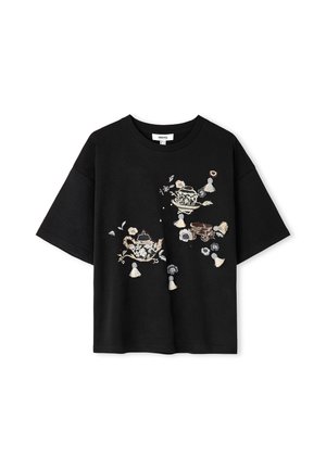 Zwart T-shirt met korte mouwen met beige en witte geborduurde theepotten, bloemen, kwastjes en kleine vlinders aan de voorkant.