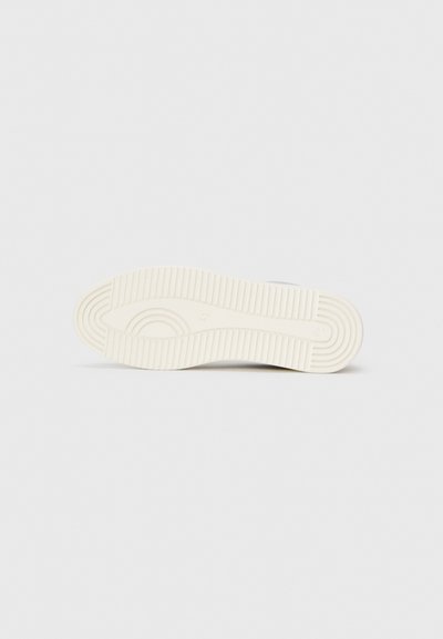 Fehér sneaker talp texturált gumis felülettel. Kör alakú és vonal menti barázdákat tartalmaz a tapadás és a fogás érdekében. Minimalista dizájn.