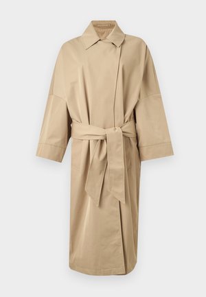 Μπεζ καμπαρντίνα μήκους μέχρι το γόνατο με φαρδιά μανίκια, γιακά με σχισμές, εμπρός τύπου κρουαζέ και ζώνη από το ίδιο ύφασμα δεμένη μέσης.