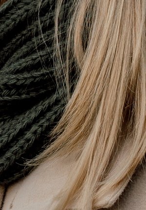 Gros plan sur des cheveux foncés tressés à côté de cheveux blonds raides, reposant tous deux sur un fond en tissu beige.