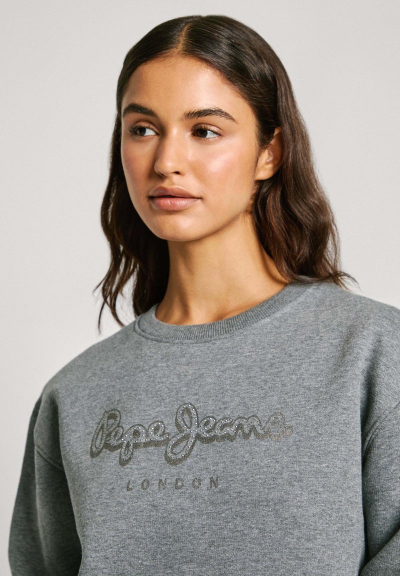 Sudadera gris con cuello acanalado, que presenta un logo metálico "Pepe Jeans" y el texto "LONDON", con textura suave y ajuste casual.