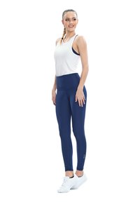 Fehér ujjatlan trikó, amelyet tengerészkék leggingsgel párosítanak; a leggings magas derekú kialakításúak, sima és rugalmas anyagból készültek.
