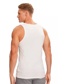 Witte tanktop van katoen, met een aansluitend design, brede schouderbanden en een gladde textuur. De achterzijde toont een subtiele, gebogen zoom.