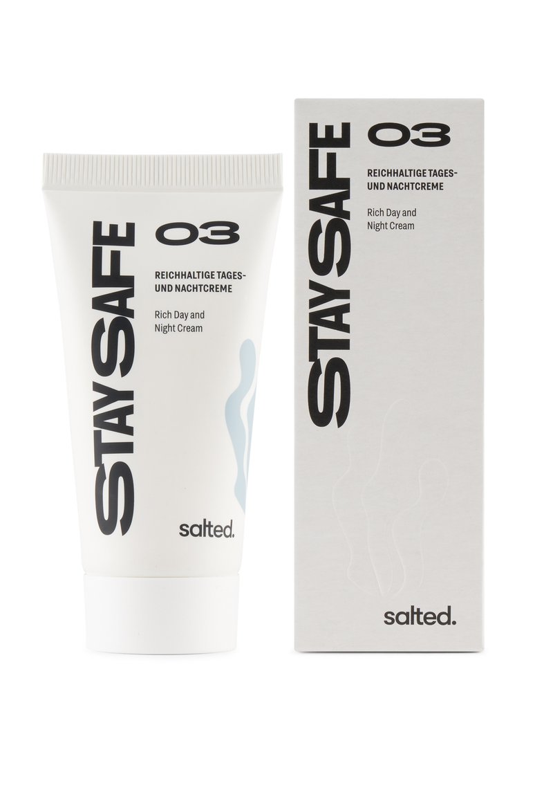 Tubo bianco con un tappo texturizzato, etichettato "STAY SAFE O3," accanto a una scatola bianca con un design minimalista e testo nero che indica "Crema Ricca Giorno e Notte."