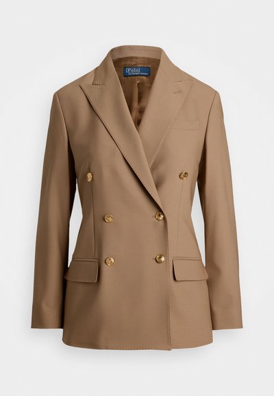 Kaksirivine bleiser heledast pruunist kangast, millel on kuldsed nupud, soonilised kraed ja kaks esi-taskut, millel on sile tekstuur.