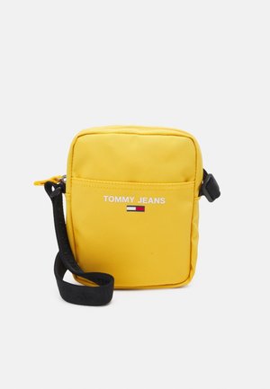 Yellow nylon crossbody bag with a black strap, featuring "TOMMY JEANS" logo and a small flag design on the front, rectangular shape.