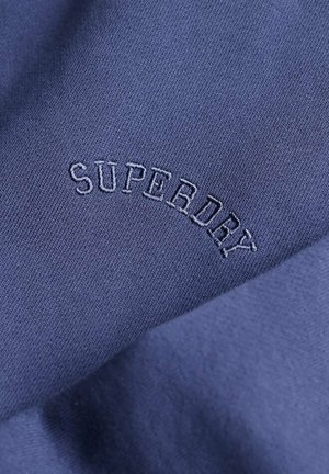 Granatowa tkanina o gładkiej fakturze, z haftowanym słowem "SUPERDRY" w zakrzywionym wzorze.
