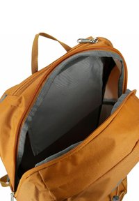 Bruine stoffen rugzak met grijze accenten; beschikt over een geavanceerd hoofdvak met rits en een handvat aan de bovenkant. De binnenkant is gevoerd met een gladde grijze stof.