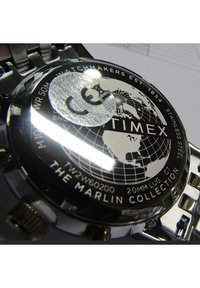 Fondo de reloj de acero inoxidable que presenta un gráfico del globo. Grabado con la marca "TIMEX" y el modelo "LA COLECCIÓN MARLIN". Resistente al agua hasta 50 m.