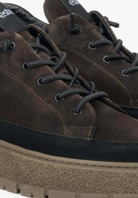 Hnědé semišové boty s černými akcenty, na kulaté tkaničky a s texturovanou platformou. Podšívka je z černé kůže. Přítomný výrazný šev.