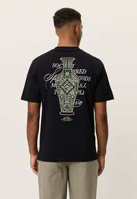 Μαύρο βαμβακερό t-shirt με μεγάλο γραφικό ενός βάζου στην πλάτη, με περίτεχνα σχέδια και στιλιζαρισμένο κείμενο σε λευκό και ανοιχτό πράσινο.