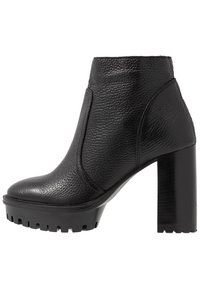 Botines negros con cuero texturizado, punta redondeada y un tacón alto y grueso con suela de goma para mayor tracción.
