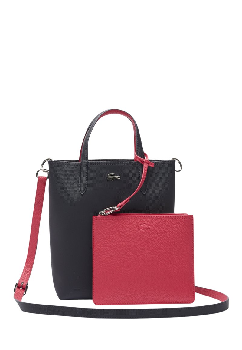 Sac en cuir noir avec des accents rouges, doté de doubles poignées, d'une bandoulière amovible et d'une pochette rouge assortie en plus petite taille.