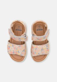 Sandal dengan pola bunga berwarna peach lembut, dilengkapi dengan tali yang dapat disesuaikan, bantalan di bagian kaki, dan sol karet putih. Label ukuran terlihat di dalam.