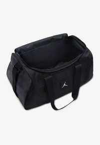 Black duffel bag made of durable fabric. Features dual handles, a zippered top, and a logo patch on the side. Spacious interior.