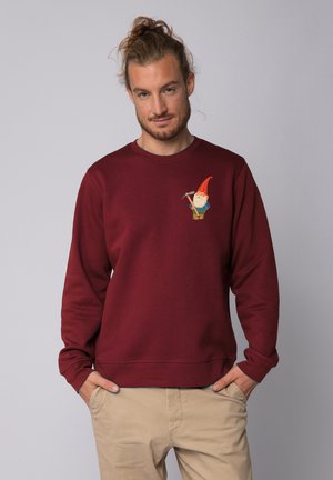 Sweat-shirt bordeaux avec un col rond, arborant un design de gnome brodé sur la poitrine gauche. Tissu doux avec une texture lisse.