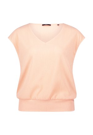 Peach-colored short-sleeve blouse with a V-neck, featuring a textured fabric and elasticized hem for a fitted appearance.