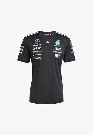 Black athletic shirt with a crew neck, featuring white stripes on shoulders and multiple sponsor logos in contrasting colors. Made of synthetic material.