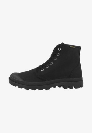 Botas de tobillo de lona negra con una puntera de goma, seis ojales para los cordones y una suela de goma texturizada. Presenta una sutil etiqueta de marca.