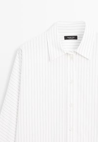 Camicia bianca con righe verticali blu, colletto classico e chiusura con bottoni. Il tessuto ha una texture liscia e una vestibilità su misura.