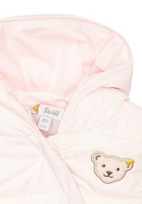 Chaqueta acolchada de color rosa claro con un diseño acolchado, presenta un parche de oso en el pecho, una capucha forrada y una etiqueta que muestra la talla 62. Material suave.