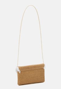 Sac en bandoulière en paille tissée avec un extérieur texturé brun, une chaîne en métal doré et des accents de franges blanches sur les côtés.