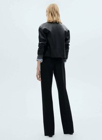 Black leather cropped jacket with long sleeves over black high-waisted trousers, featuring a straight-leg design and a smooth texture.