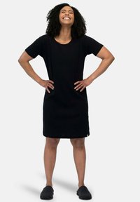 Vestito nero a maniche corte con una vestibilità comoda, realizzato in tessuto testurizzato, con scollo rotondo e spacco laterale, abbinato a ciabatte grigie.