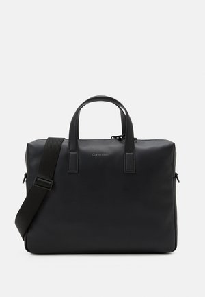 Schwarze Laptoptasche mit glatter, lederähnlicher Oberfläche, doppelten oberen Griffen, abnehmbarem Gurt, Reißverschlussverschluss und subtilen Calvin Klein Logo-Details.