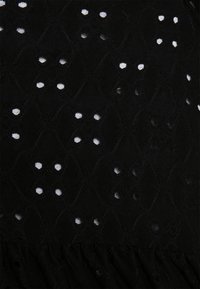 Tissu noir avec un motif en losange comportant de petits groupes symétriques de quatre trous créant une texture semblable à de la dentelle.