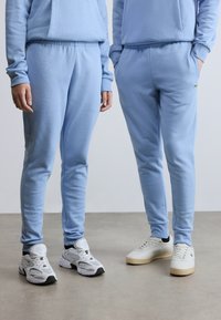 Ανοιχτό μπλε φούτερ και ταιριαστό φόρμα από μαλακό ύφασμα. Διαθέτουν ριμπ ζώνη μέσης και κεντημένο λογότυπο στα παντελόνια φόρμας. Αθλητικά παπούτσια σε λευκό και κρεμ χρώμα.