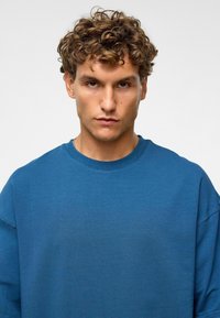 Blauwe katoenen sweatshirt met een ronde hals, ontspannen pasvorm en raglanmouwen. Effen structuur zonder zichtbare patronen of hardware details.