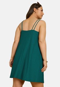 Teal ribbat klänning med justerbara dubbla spagettiband, utsvängd A-linjeformad silhuett och strukturerat tygdetalj.