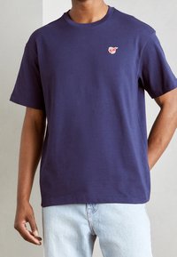 Marineblå t-shirt med korte ærmer lavet af bomuld, med et lille broderet logo på venstre bryst og en afslappet pasform.