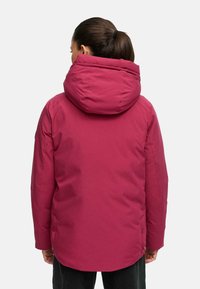 Gewatteerde jas in diep roze met een grote, opvouwbare capuchon. Voorzien van een gladde textuur, zijknopen en een middellange snit.