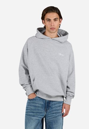 Grå hettegenser med kengurulomme, raglanermer og subtile logodetaljer. Kombinert med lyseblå denimjeans.