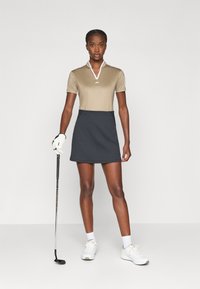 Bežna polo majica s kratkimi rokavi in belim ovratnikom, v kombinaciji s temnosivim golf krilom. Bele rokavice in čevlji dopolnjujejo outfit.